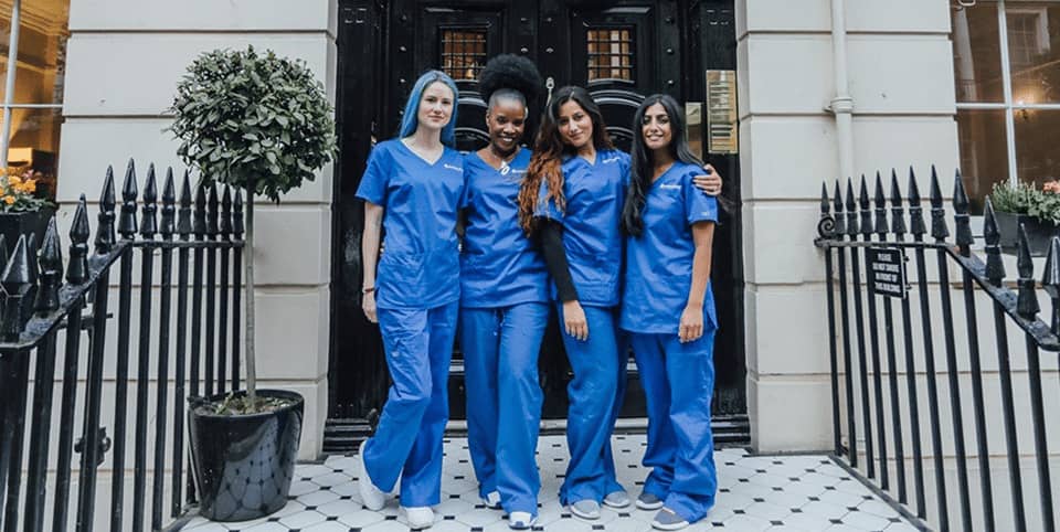 Four nurses in blue scrubs outside a Georgian clinic entrance for Morpheus8 skin remodelling in Amsterdam